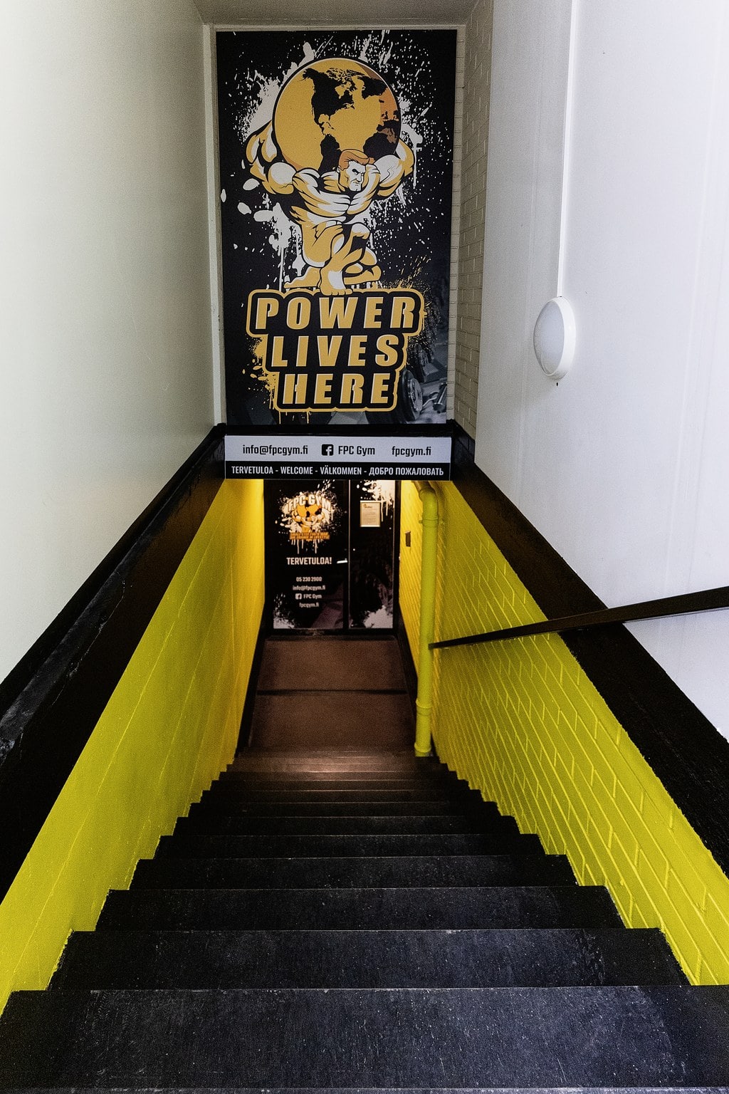 Power Lives Here -kannattimen kuva FPC GYM:stä Hamina, joka korostaa voimaa ja harjoittelua.